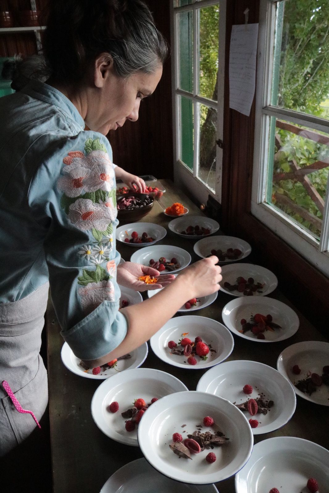 Chef argentina emplatando frutos rojos y flores comestibles en cocina federal · Homenaje al oficio real